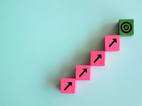 Target and focus concept. Wooden cubes line upward with arrow and dart target on green background.
