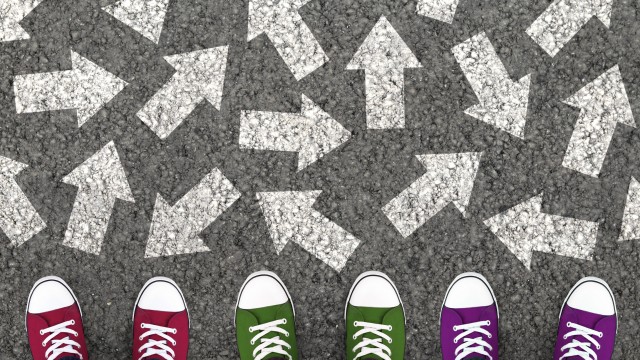 Team Standing With Many Direction Arrows Choices On The Road, Representing Plenty Of Ideas And Solutions