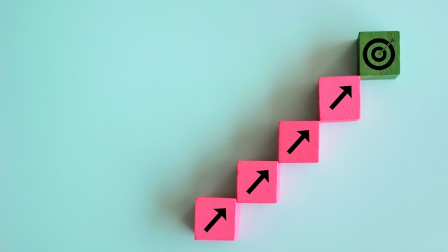 Target and focus concept. Wooden cubes line upward with arrow and dart target on green background.