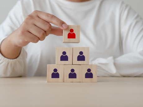 Concept and idea of leadership one in red among followers in dark blue wooden blocks. The top of square wooden toy cube blocks is leader of all blue representing as followers.