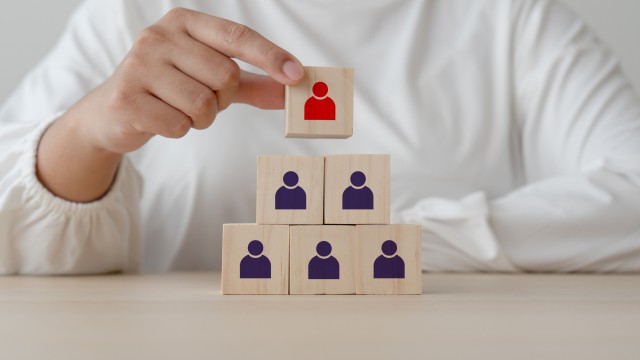 Concept and idea of leadership one in red among followers in dark blue wooden blocks. The top of square wooden toy cube blocks is leader of all blue representing as followers.